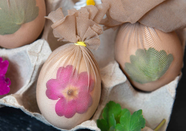 Preparación de huevos de Pascua antes de pintar con un patrón de hierbas frescas, flores. - Foto, Imagen