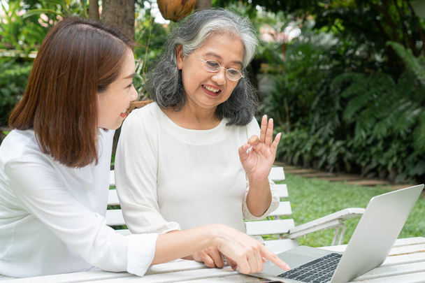 Aziatische dochter onderwijs oude oudere vrouw gebruik online Social media in computer laptop na pensionering. Begrip leertechnologie en aanpassing van ouderen - Foto, afbeelding