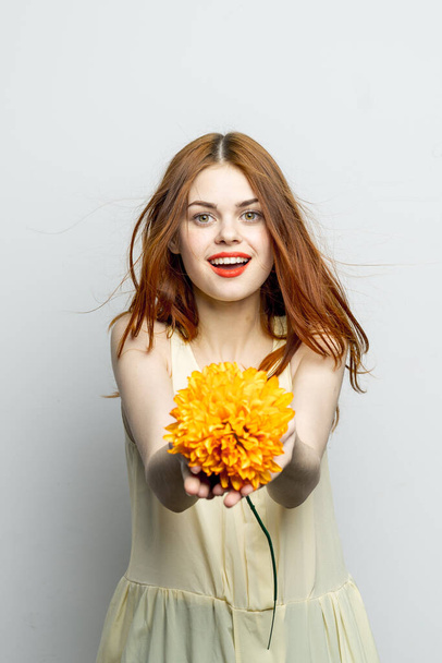 vidám szép nő egy nagy sárga virág a kezében érzelmek piros ajkak szórakoztató varázsa - Fotó, kép