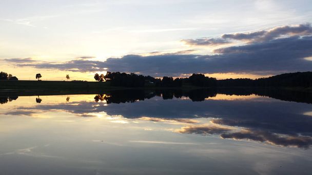 Туманне озеро - спокійна водна поверхня озера відображає небо жовтими і синіми хмарами після заходу сонця. Фільтр розмивання, простір для копіювання
. - Фото, зображення