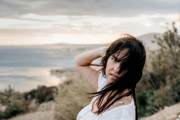 A young Croatian woman enjoying the wind on the coast of a sea during sunset - Foto, immagini