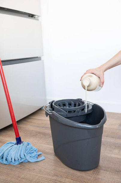 Primo piano di donna mano mettendo detergenti per pavimenti nella fibbia mop. Concetto di pulizia a casa - Foto, immagini