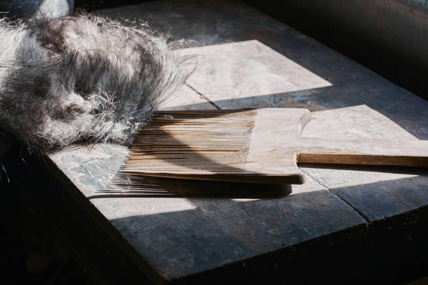  Un peine de lana artificial hecho a mano de madera. Concepto de fabricación hecho a mano - Foto, Imagen