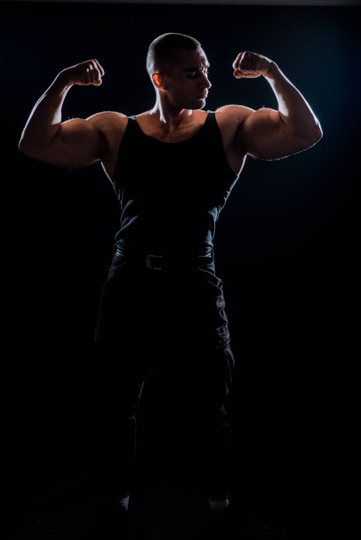Muscular super-high level handsome man posing in studio isolated on black background - 写真・画像