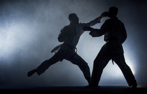 Mladý sportovní muž v bílém kimono trénink karate kata pohyby v tělocvičně - Fotografie, Obrázek