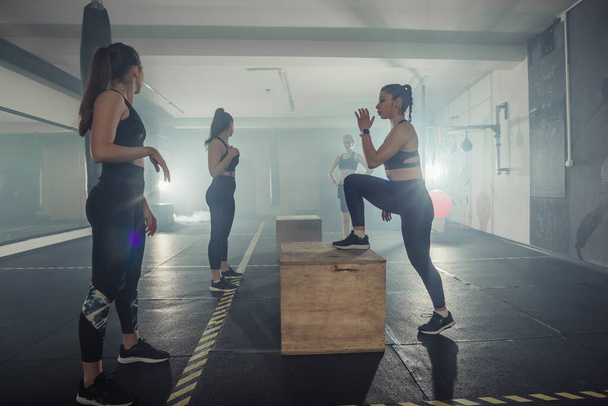 Négy sportoló nő többfunkciós edzést tart egy sportklubban. - Fotó, kép