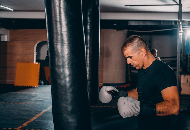 Mladý muž v boxerských rukavicích. Bojovník připraven k boji. Box, cvičení, svaly, síla, síla - koncept silového tréninku - Fotografie, Obrázek