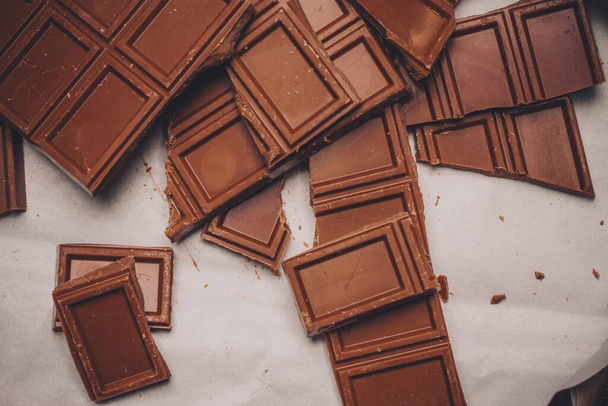 шоколад розбитий на коричневому папері на делікатному столі
 - Фото, зображення