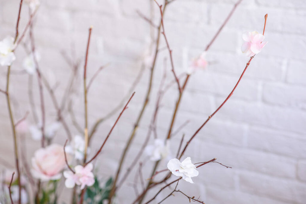 décorations de branches avec de belles fleurs roses et blanches dans le panier sur le fond d'un mur de briques blanches. décor de la maison - Photo, image