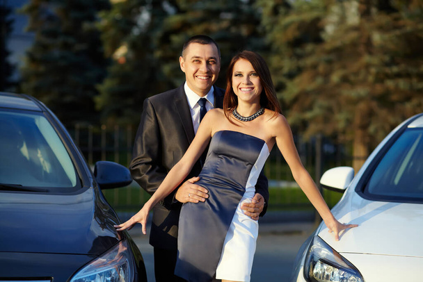 portrait of a young couple on a date standing near cars. - Фото, изображение