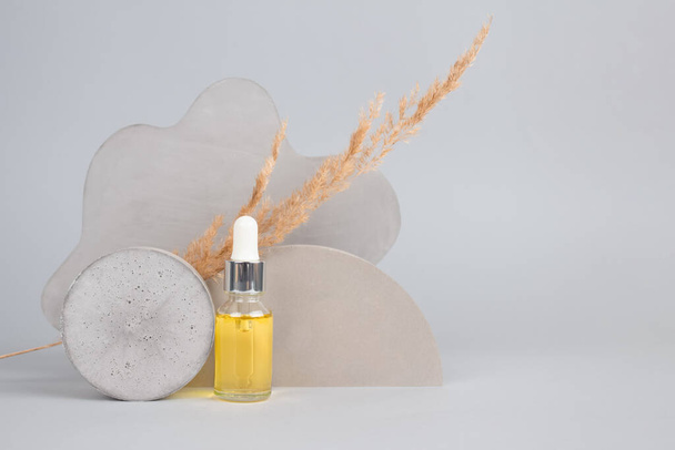 Mockup image of dropper bottle with modern organic cosmetics - polyglutamic or hyaluronic acid, serum, moisturizer, facial anti-aging oil. Trendy neutral gray still life composition - Photo, Image