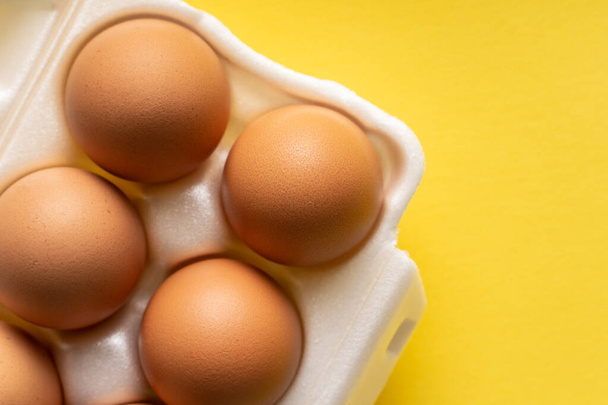 Top pohled čerstvé organické vejce v krabici kontejner na žlutém pozadí - Fotografie, Obrázek