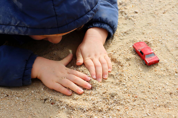 Las manos del niño están jugando con arena. Pequeñas palmeras de bebé de cerca.  - Foto, Imagen