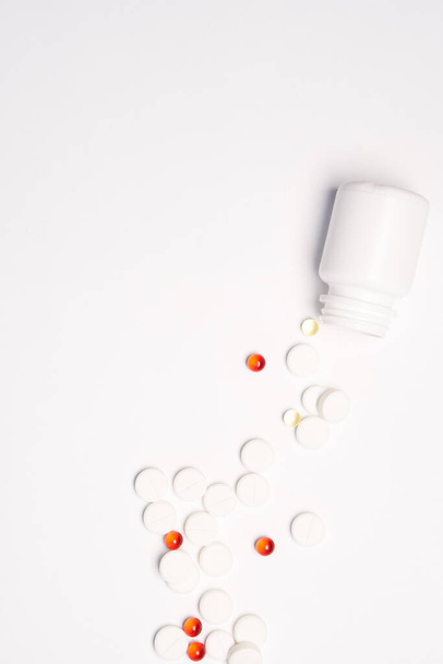 Bílá sklenice s pilulkami na lehkém pozadí horní pohled lék zdraví vitamíny - Fotografie, Obrázek