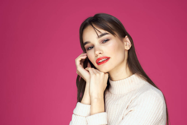 Brunette with long hair red lips cosmetics white sweater pink background cropped view - Fotografie, Obrázek