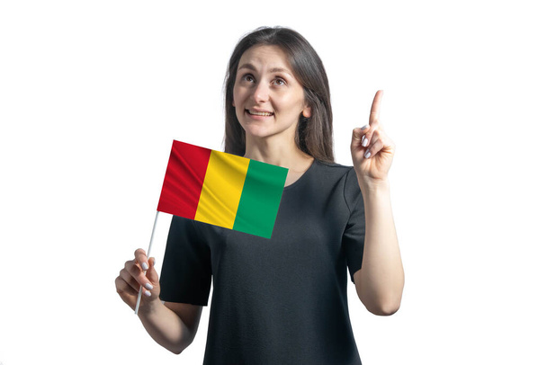Heureuse jeune femme blanche tenant le drapeau de Guinée et pointant les pouces isolés sur un fond blanc. - Photo, image