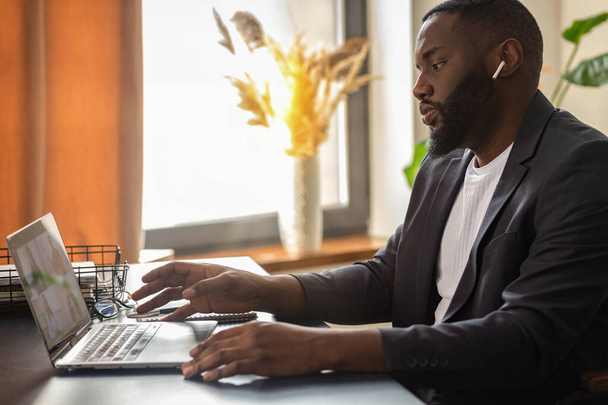 African American man is participating in an online conference sitting at the table at home. Remote work, self-isolation concept - Foto, Imagem