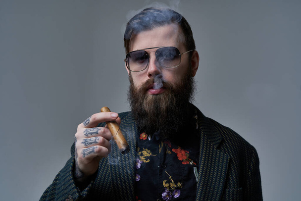 Hipster style et barbu personne avec cigare cubain en arrière-plan gris - Photo, image