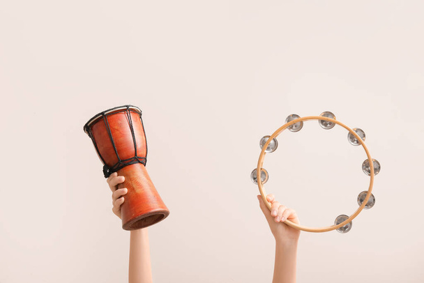 Woman holding tambourine and djembe on color background - 写真・画像