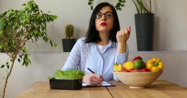 Voedingsdeskundige, diëtistische vrouw spreken en schrijven van een dieet plan, met gezonde groenten en fruit, gezondheidszorg en dieet concept. Vrouwelijke voedingsdeskundige aan haar bureau. - Video