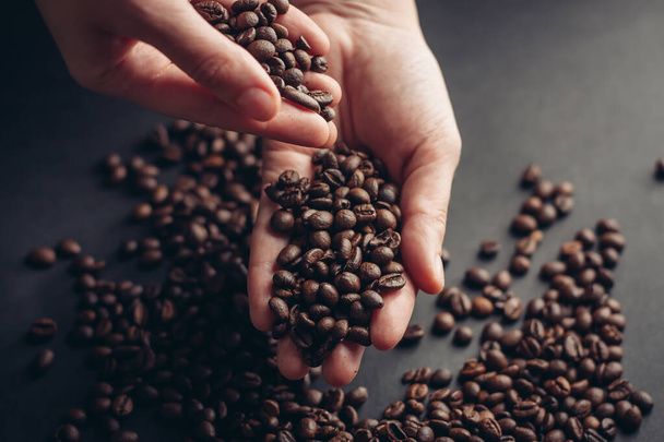 coffee beans in hands scattered on a dark background - Photo, Image