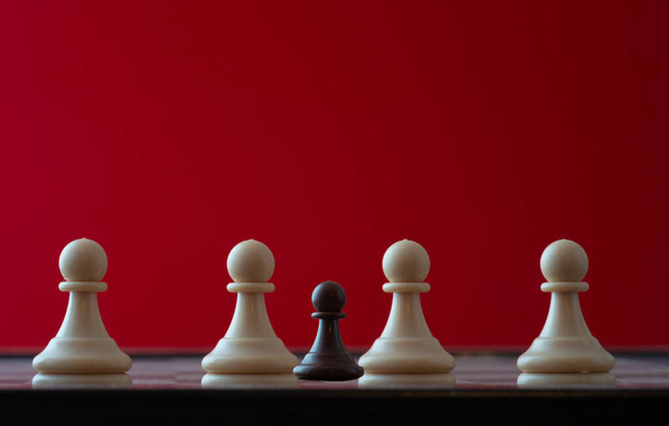 mały pionek na szachownicy przeciwko większej koncepcji przeciwnika przeciwności losu, dyscyplinacji, równości . - Zdjęcie, obraz