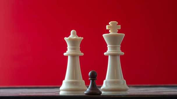 kleine pion op schaakbord tegen grotere tegenstander begrip van tegenslag, disciminatie, gelijkheid . - Foto, afbeelding