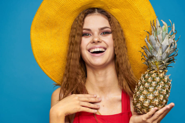 Woman in yellow hat with pineapple in hands emotions fun lifestyle summer fruit blue background - Fotoğraf, Görsel