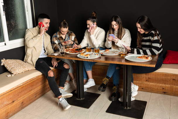 grupa młodych ludzi używa telefonów komórkowych w pizzerii - Zdjęcie, obraz