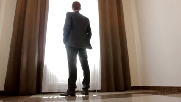 Stilvoller Mann im schwarzen Anzug schaut aus dem Fenster - Filmmaterial, Video