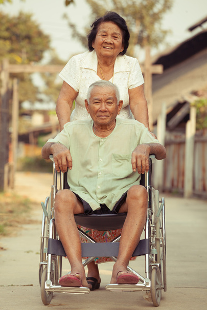 Старшая женщина толкает свою инвалидную повязку на инвалидном кресле
 - Фото, изображение