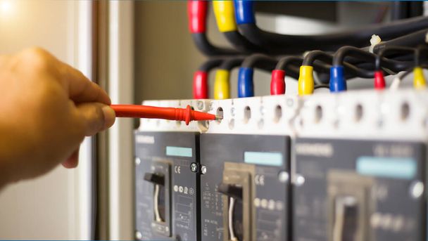 Elektrotechnicus test de werking van de elektrische schakelkast regelmatig voor onderhoud. - Foto, afbeelding
