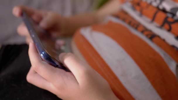 Παιδί κρατά Smartphone στα χέρια, Πιέζει την οθόνη με τα δάχτυλα. Αναπαραγωγή βιντεοπαιχνιδιών - Πλάνα, βίντεο