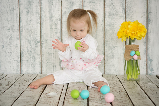 Menina com síndrome de Down está segurando ovos de Páscoa
 - Foto, Imagem