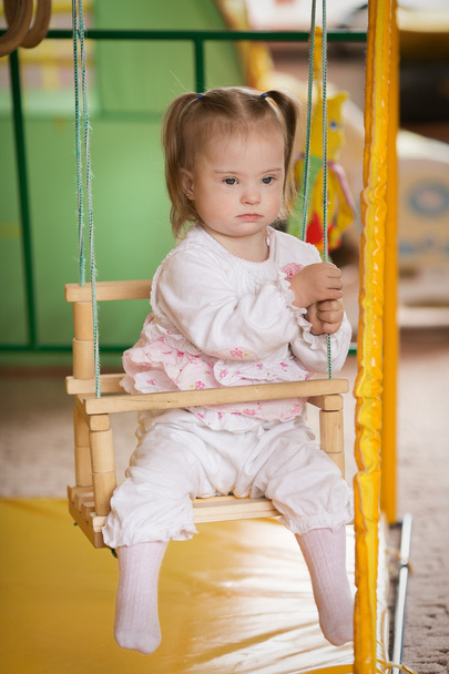 Chica con síndrome de Down está montando en un columpio
 - Foto, Imagen