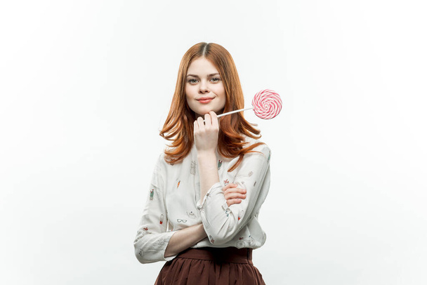pretty woman with red hair holding lollipop sweets enjoying sweets - Foto, afbeelding
