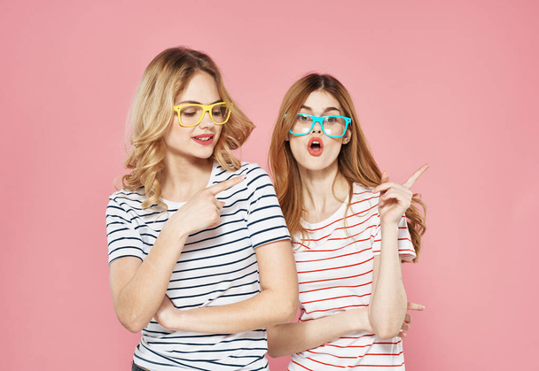 Two women in striped T-shirts trendy glasses communication Friendship together pink background - Zdjęcie, obraz
