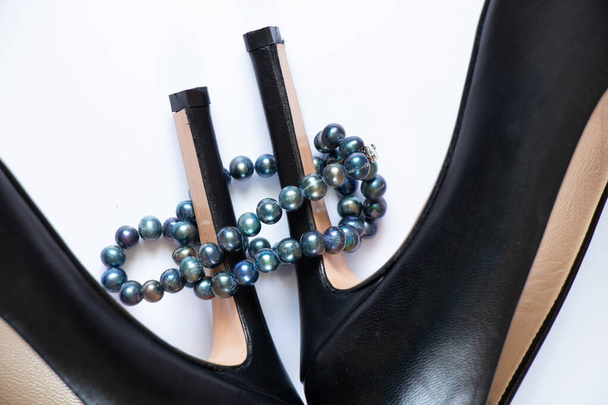 zapatos femeninos de cuero negro y perlas sobre un fondo blanco, belleza y moda - Foto, imagen