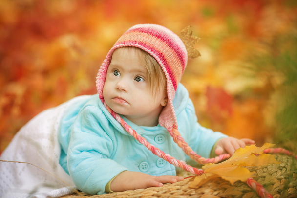 Baby with Down syndrome is resting in autumn forest - Фото, зображення
