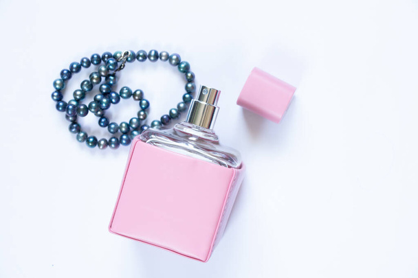 Perfume de mujer y cuentas de perlas sobre fondo blanco, eau de toilette - Foto, imagen