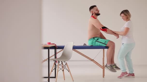 Doctor plakband op een zere plek van een elleboog na een blessure in de training - Video