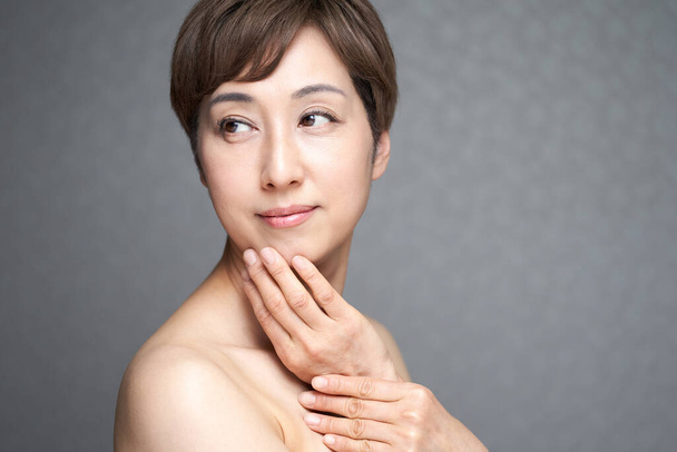 Femme japonaise d'âge moyen mettant sa main sur son menton - Photo, image