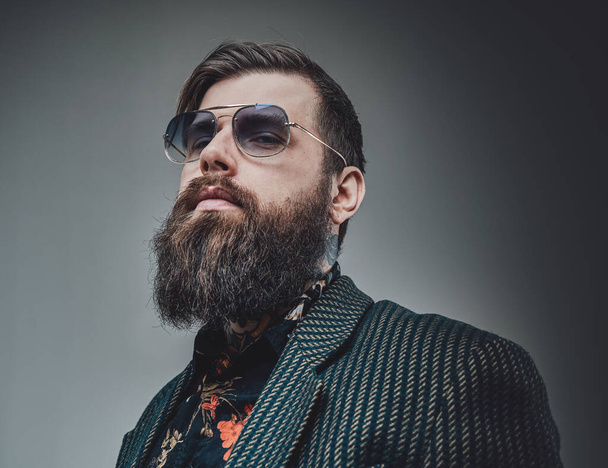 Elegant and bearded guy with sunglasses wearing suit in studio - Photo, Image