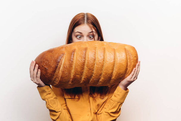 mulher feliz com um pão na mão um pão em uma posição horizontal em um fundo leve - Foto, Imagem