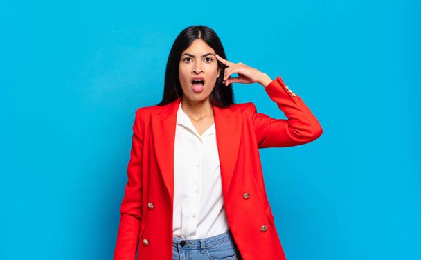 young hispanic businesswoman looking surprised, open-mouthed, shocked, realizing a new thought, idea or concept - Фото, изображение