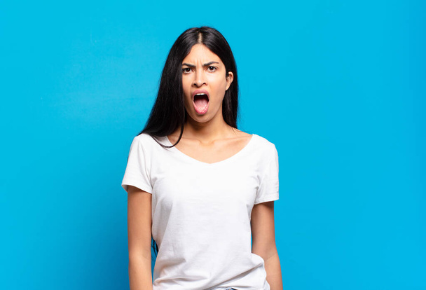 young pretty hispanic woman looking shocked, angry, annoyed or disappointed, open mouthed and furious - Fotoğraf, Görsel