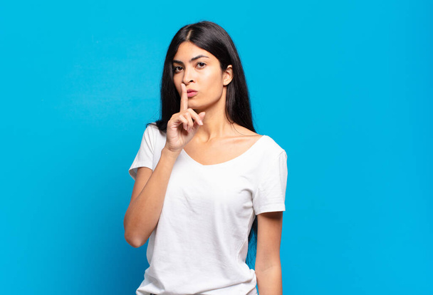 young pretty hispanic woman asking for silence and quiet, gesturing with finger in front of mouth, saying shh or keeping a secret - Foto, immagini