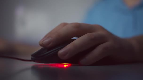 Il primo piano di una mano di uomo lavora a casa di sera, clicca sui pulsanti di un topo di computer, gira una pergamena - Filmati, video