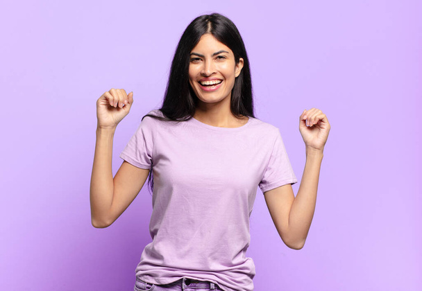 young pretty hispanic woman feeling happy, positive and successful, celebrating victory, achievements or good luck - 写真・画像