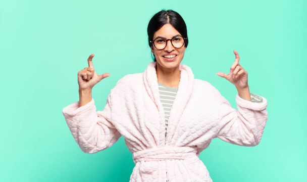 young pretty woman framing or outlining own smile with both hands, looking positive and happy, wellness concept. pajamas concept - Valokuva, kuva